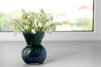 Photo of Beautiful lily of the valley bouquet in vase on windowsill, space for text