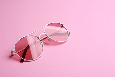 Stylish sunglasses on pink background, space for text. Fashionable accessory