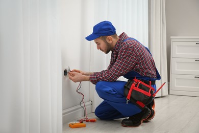 Photo of Professional electrician with tester checking voltage in room