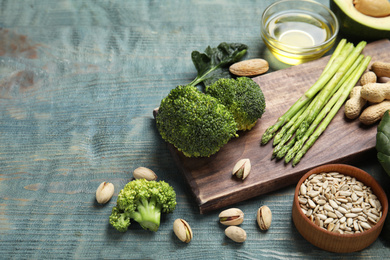 Photo of Different products rich in vitamin E on blue wooden table, space for text