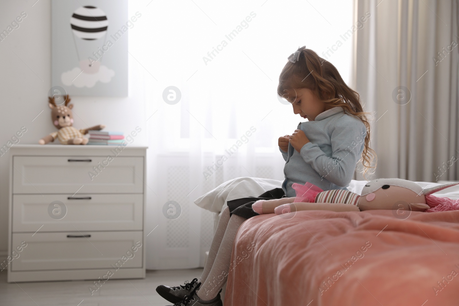 Photo of Little girl getting ready for school in bedroom