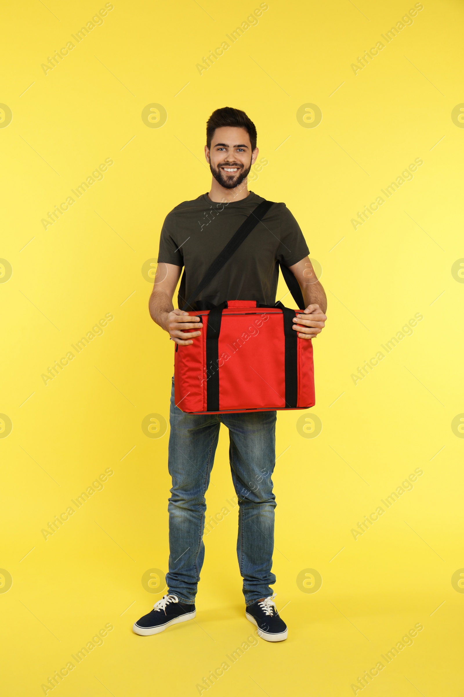 Photo of Young courier with thermo bag on color background. Food delivery service