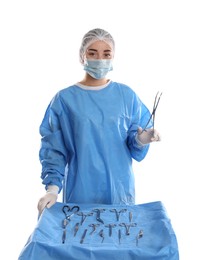 Doctor holding medical clamps near table with different surgical instruments on light background