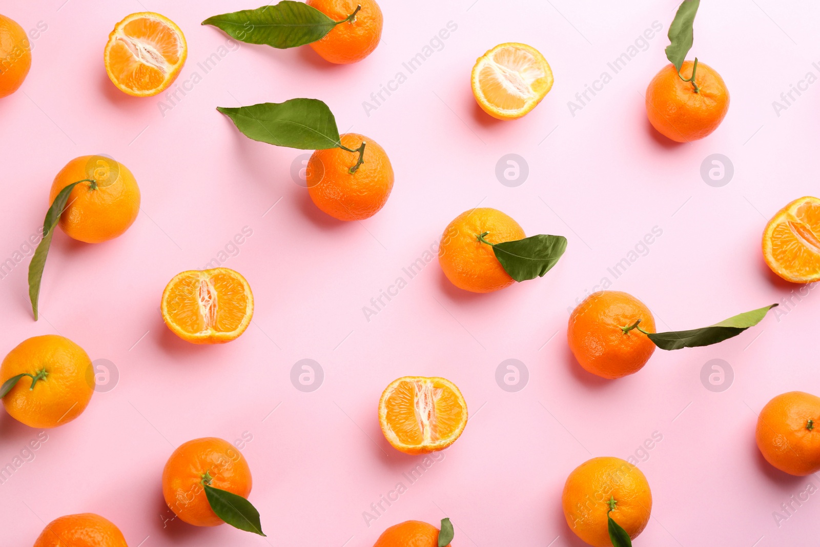 Photo of Fresh ripe tangerines with green leaves on pink background, flat lay