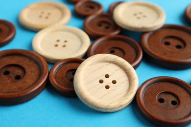 Photo of Many colorful sewing buttons on light blue background, closeup