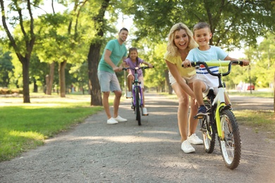 Photo of Happy parents teaching their children to ride bicycle in park