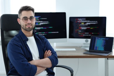 Photo of Happy young programmer working at desk in office