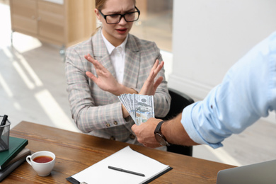 Photo of Businesswoman refuses to take bribe money at table in office