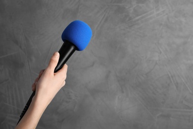 Woman holding microphone on color background, space for text