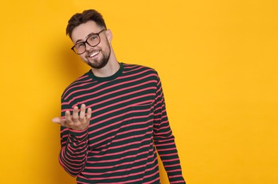Photo of Handsome man in striped sweatshirt gesturing on yellow background, space for text