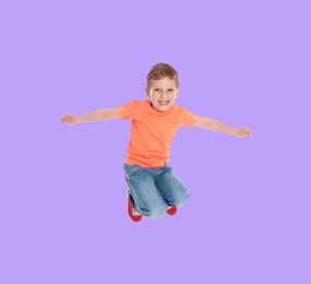 Happy boy jumping on light violet background, full length portrait
