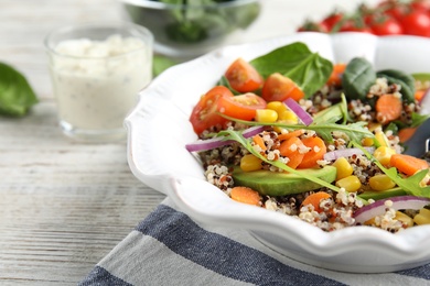 Photo of Healthy quinoa salad with vegetables in plate on table, closeup. Space for text
