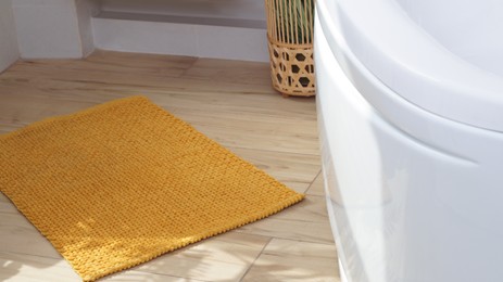 Soft bath mat near tub on wooden floor in bathroom