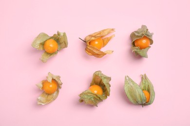 Ripe physalis fruits with dry husk on pink background, flat lay