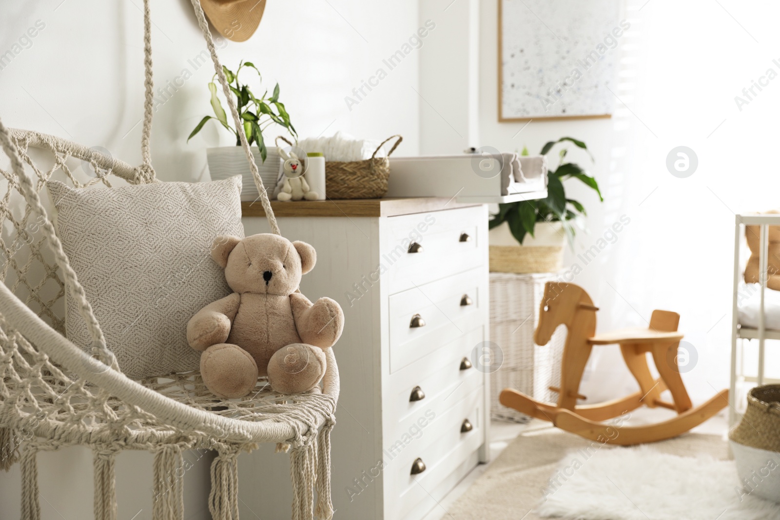 Photo of Stylish swing and changing table in baby room. Interior design