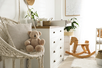 Photo of Stylish swing and changing table in baby room. Interior design