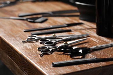 Photo of Hairdresser tools. Different scissors and combs on wooden table, closeup