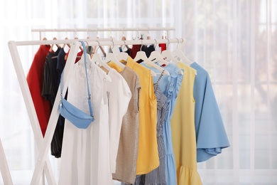 Racks with stylish clothes in light room