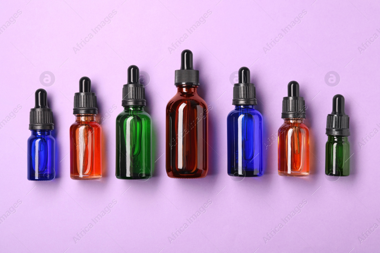 Photo of Bottles of essential oils on color background, flat lay. Cosmetic products