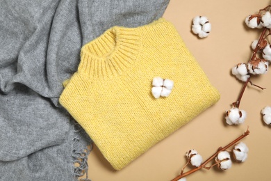 Photo of Warm sweater, scarf and cotton flowers on beige background, flat lay. Autumn season