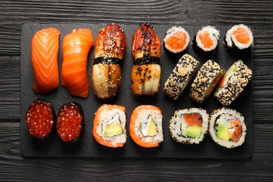 Photo of Set of delicious sushi rolls on black wooden table, top view