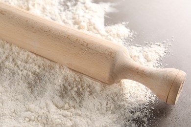 Photo of Scattered flour and rolling pin on grey textured table, closeup