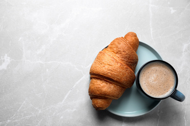 Photo of Fresh croissant and coffee on light grey marble table, top view. Space for text