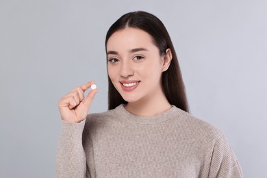 Photo of Happy woman with pill on gray background