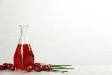 Palm oil in glass bottle, tropical leaf and fruits on light table. Space for text