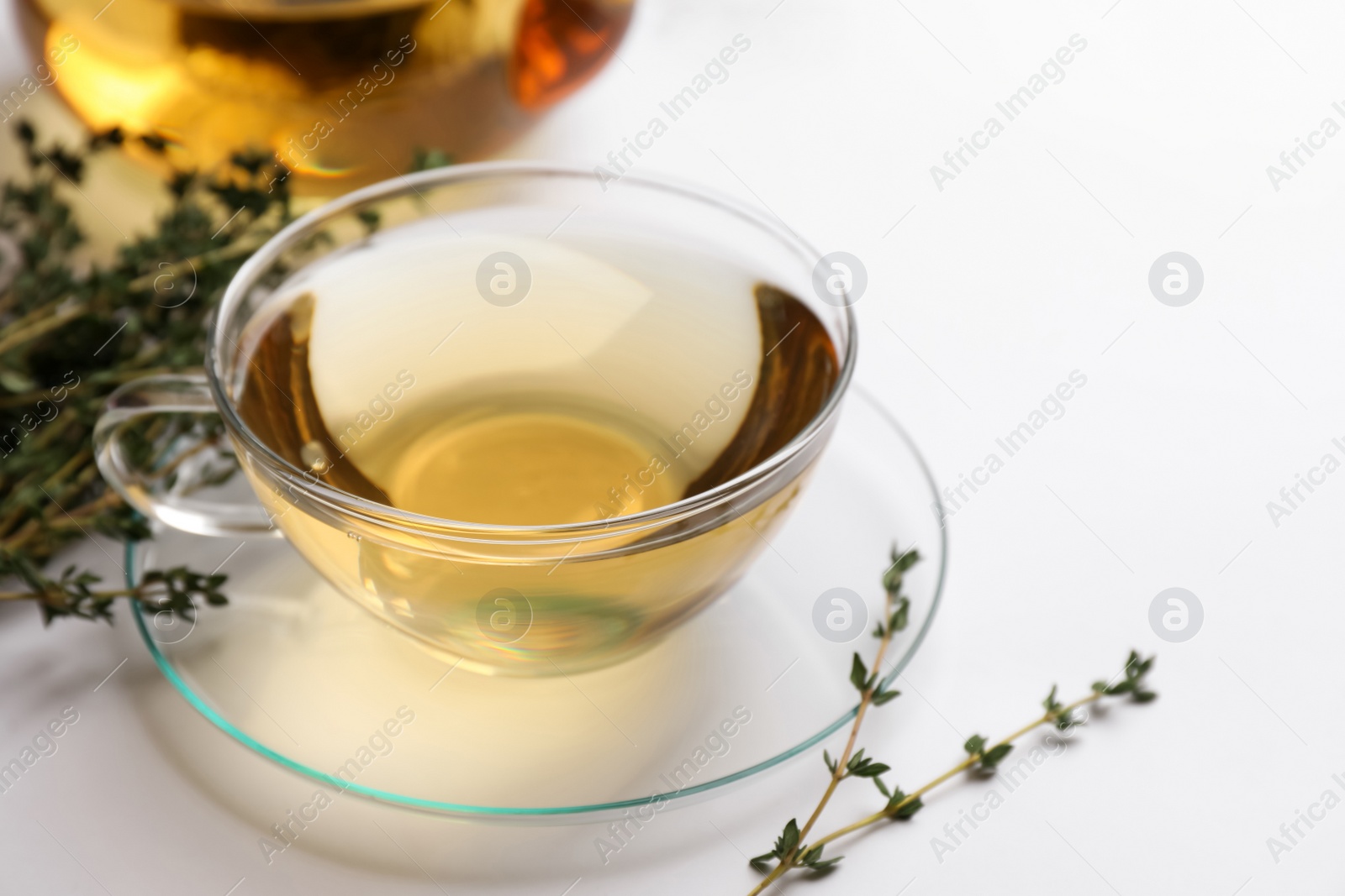 Photo of Cup of aromatic herbal tea with thyme on white table