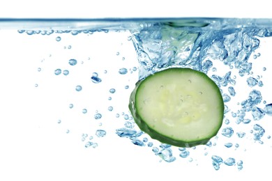 Photo of Slices of fresh cucumber falling into water on white background, closeup