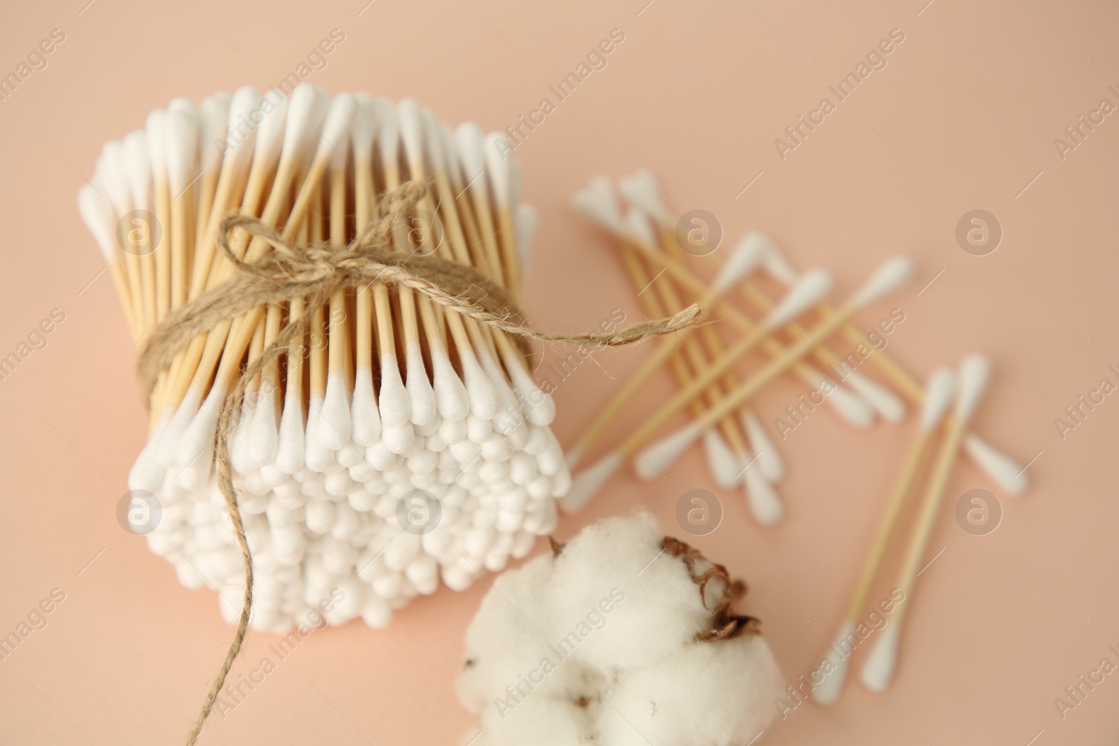 Photo of Many cotton buds and flower on beige background, closeup