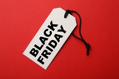 White tag with phrase BLACK FRIDAY on red background, top view