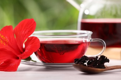 Photo of Delicious hibiscus tea and flowers on white wooden table, closeup