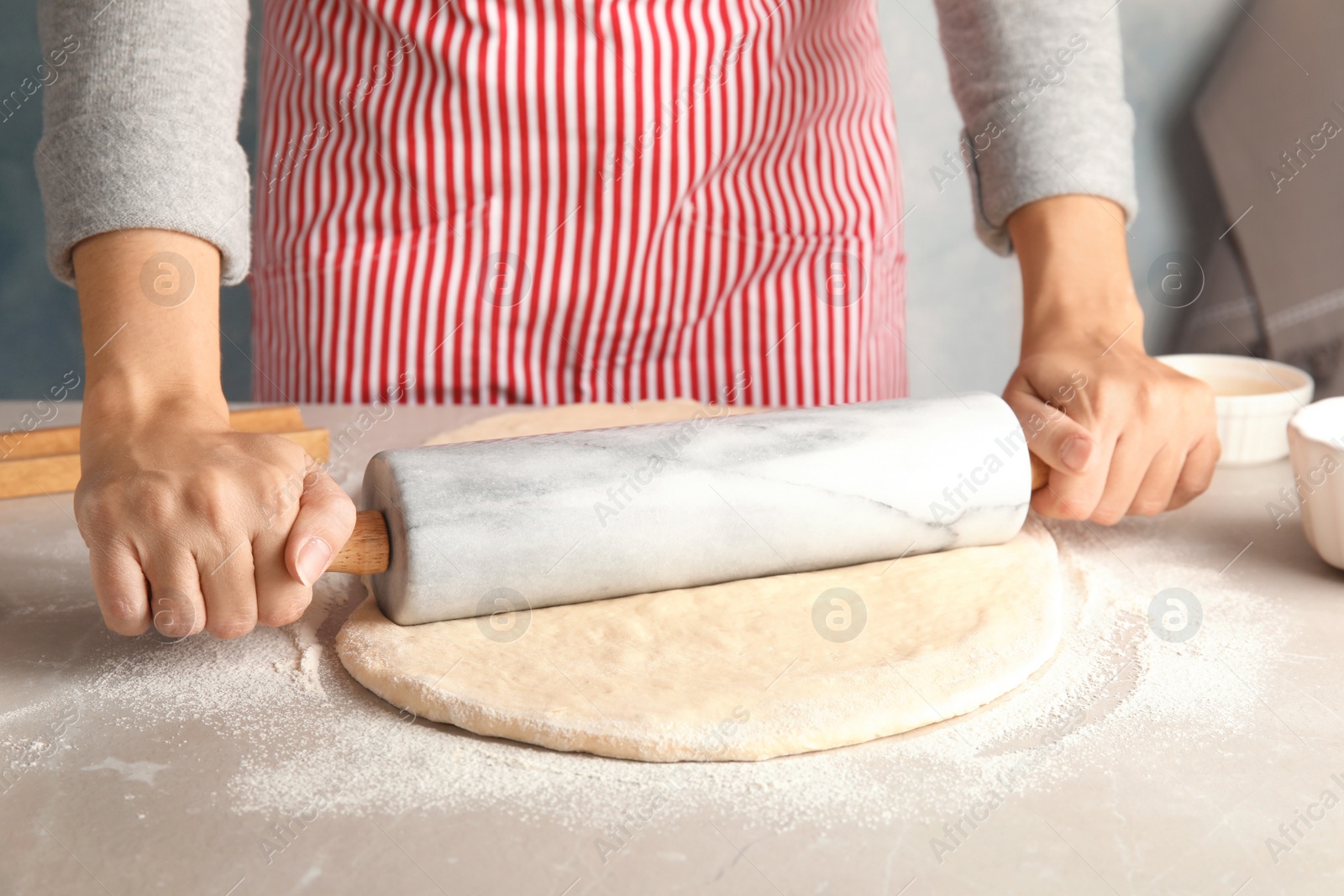 Photo of Woman rolling dough for cinnamon rolls on table, closeup