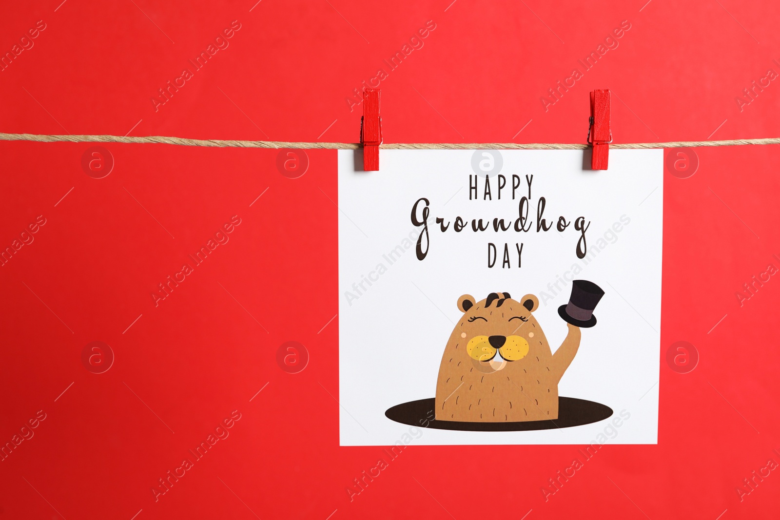 Photo of Happy Groundhog Day greeting card hanging on red background, space for text