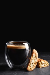 Photo of Tasty cantucci and cup of aromatic coffee on black table. Traditional Italian almond biscuits