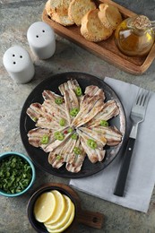 Photo of Tasty pickled anchovies served on textured table, flat lay