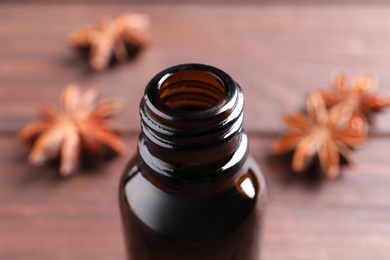 Photo of Anise essential oil in bottle on table, closeup