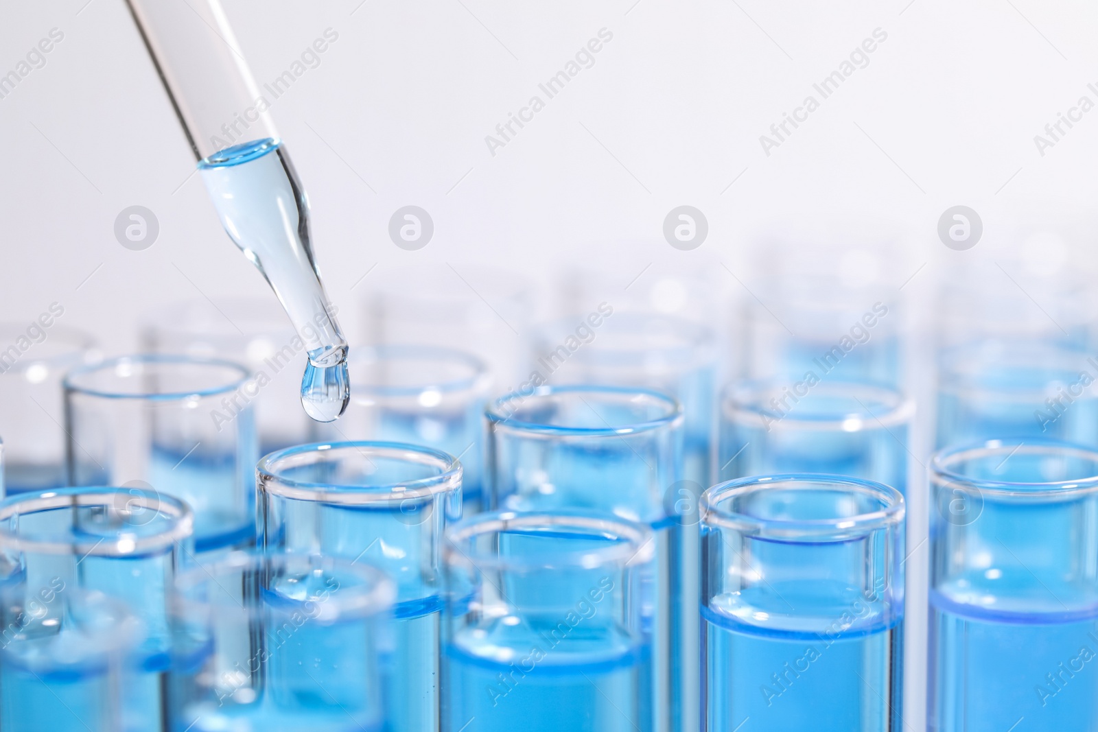 Photo of Dripping reagent into test tube on light background, closeup and space for text. Laboratory analysis