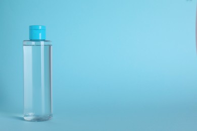 Photo of Bottle of micellar water on light blue background. Space for text