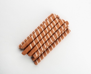 Delicious chocolate wafer rolls on white background, top view. Sweet food