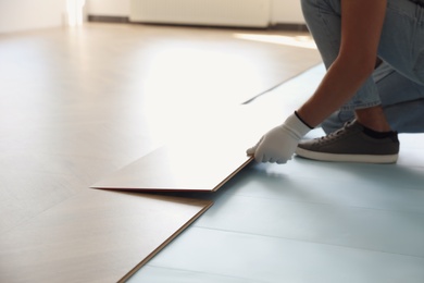 Worker installing laminated wooden floor indoors, closeup