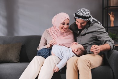 Photo of Happy Muslim family with little son in living room