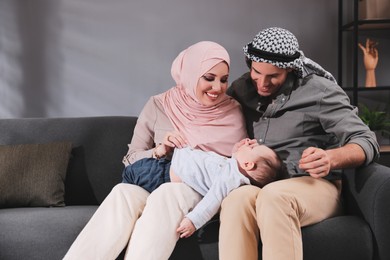 Happy Muslim family with little son in living room