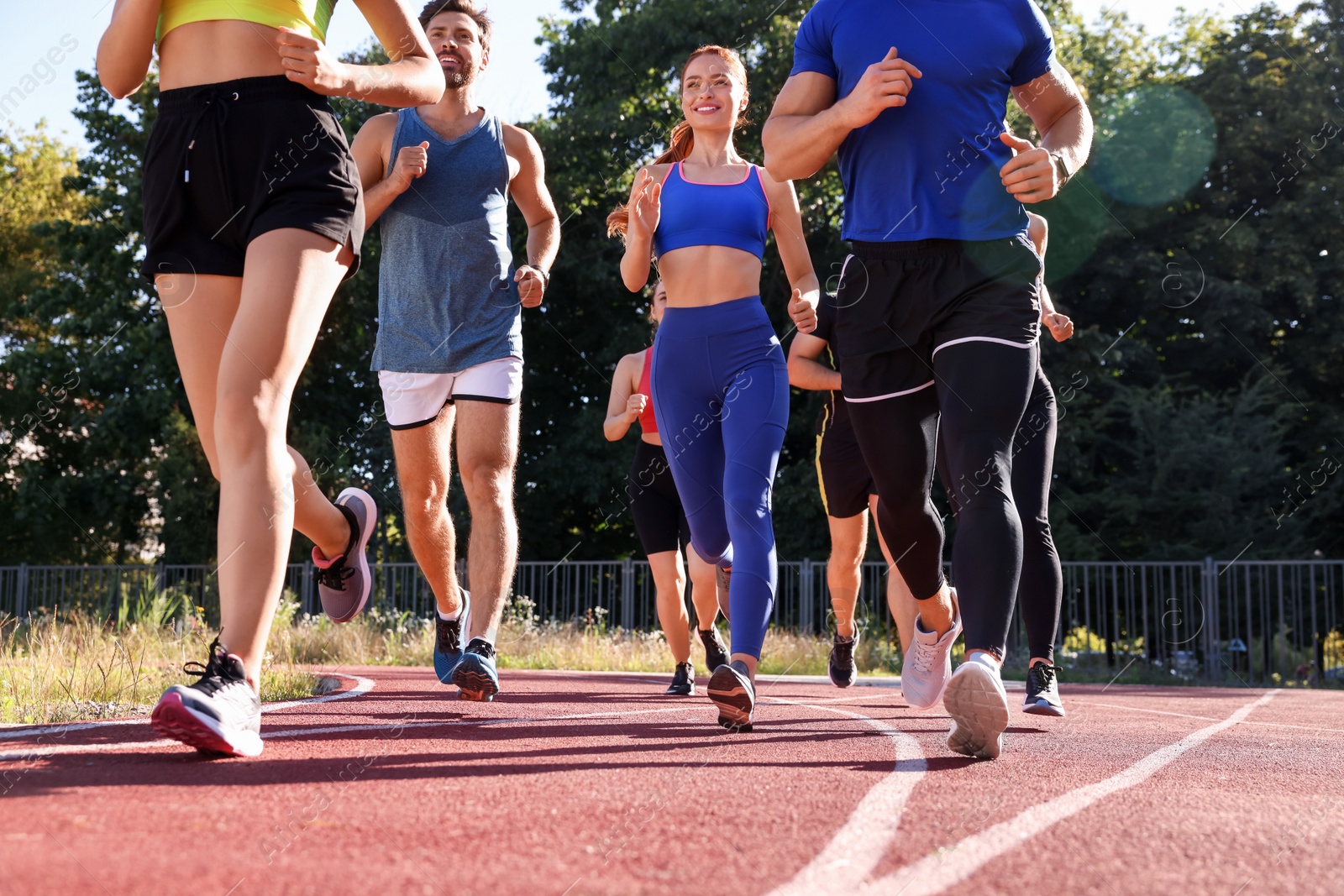 Photo of Group of people running at stadium on sunny day