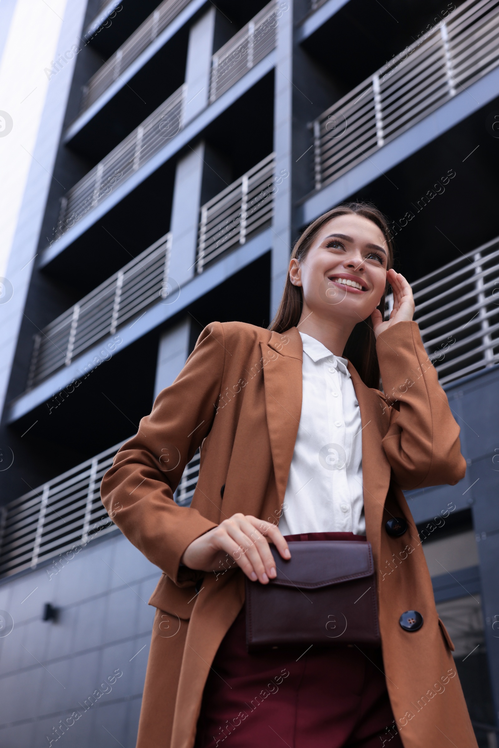 Photo of Young woman in formal clothes near building outdoors, low angle view