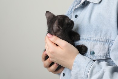 Photo of Woman with cute fluffy kitten on grey background, closeup. Space for text
