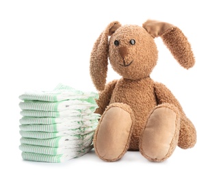 Photo of Stack of diapers and toy bunny on white background. Baby accessories