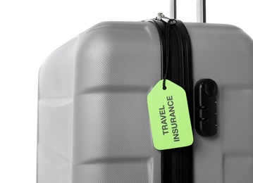 Grey suitcase with TRAVEL INSURANCE label on white background, closeup